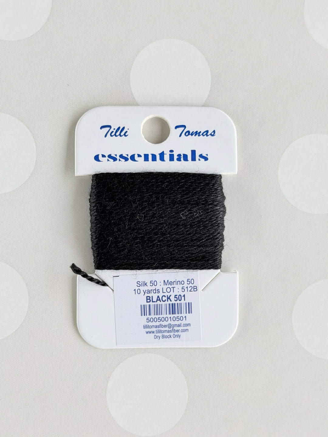 Black yarn on a Tilly thomas's label against a light gray background